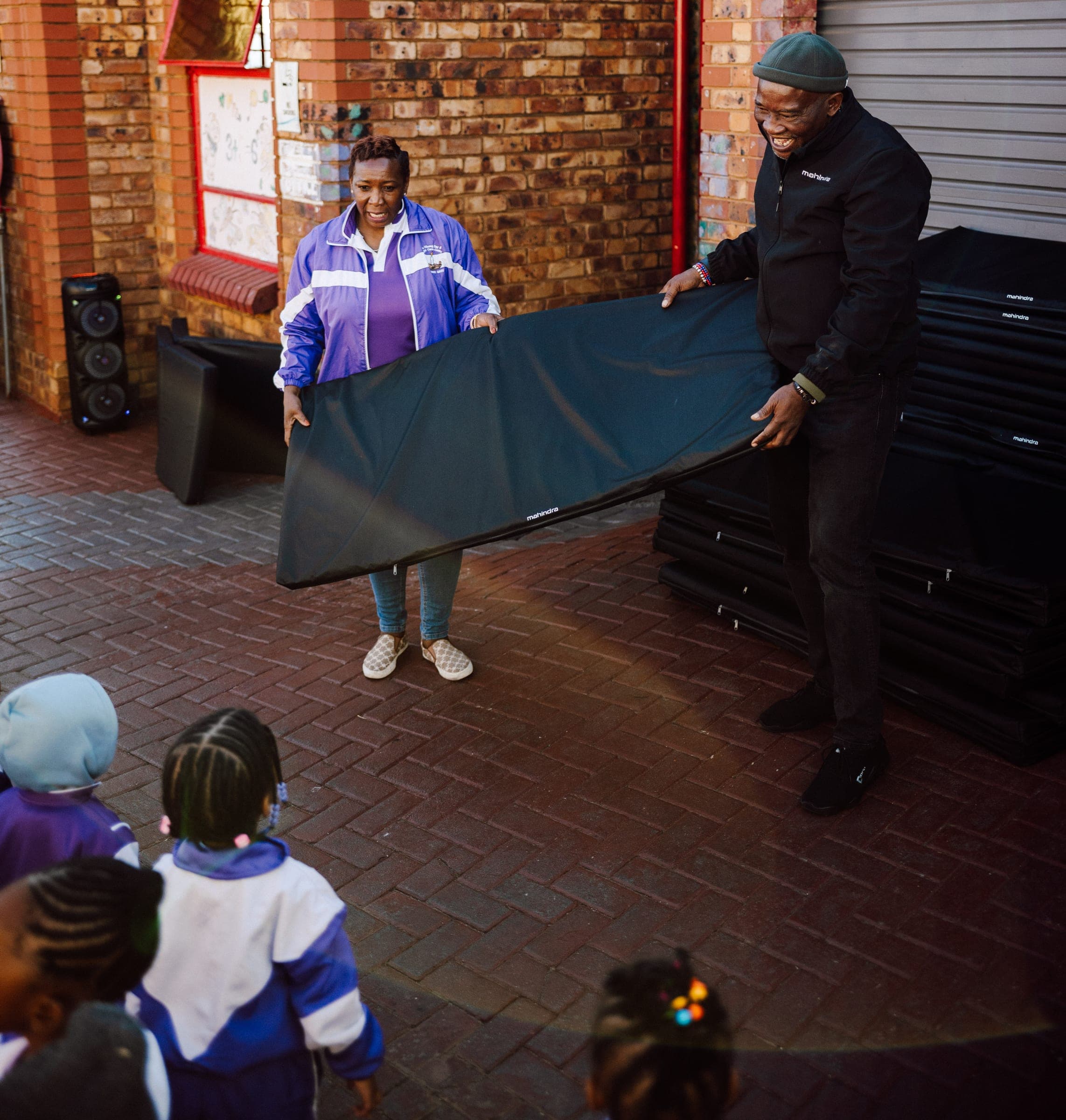 Mahindra team presenting branded mats to children at Ba-Tliseng Day and Night Care