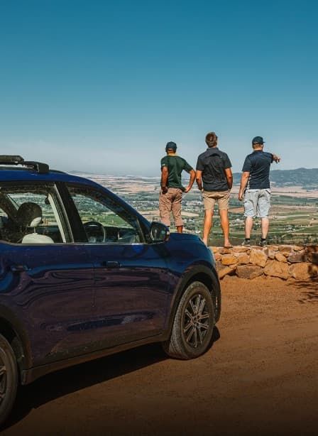 Mahindra XUV700 parked at a mountain lookout with two friends taking in the view