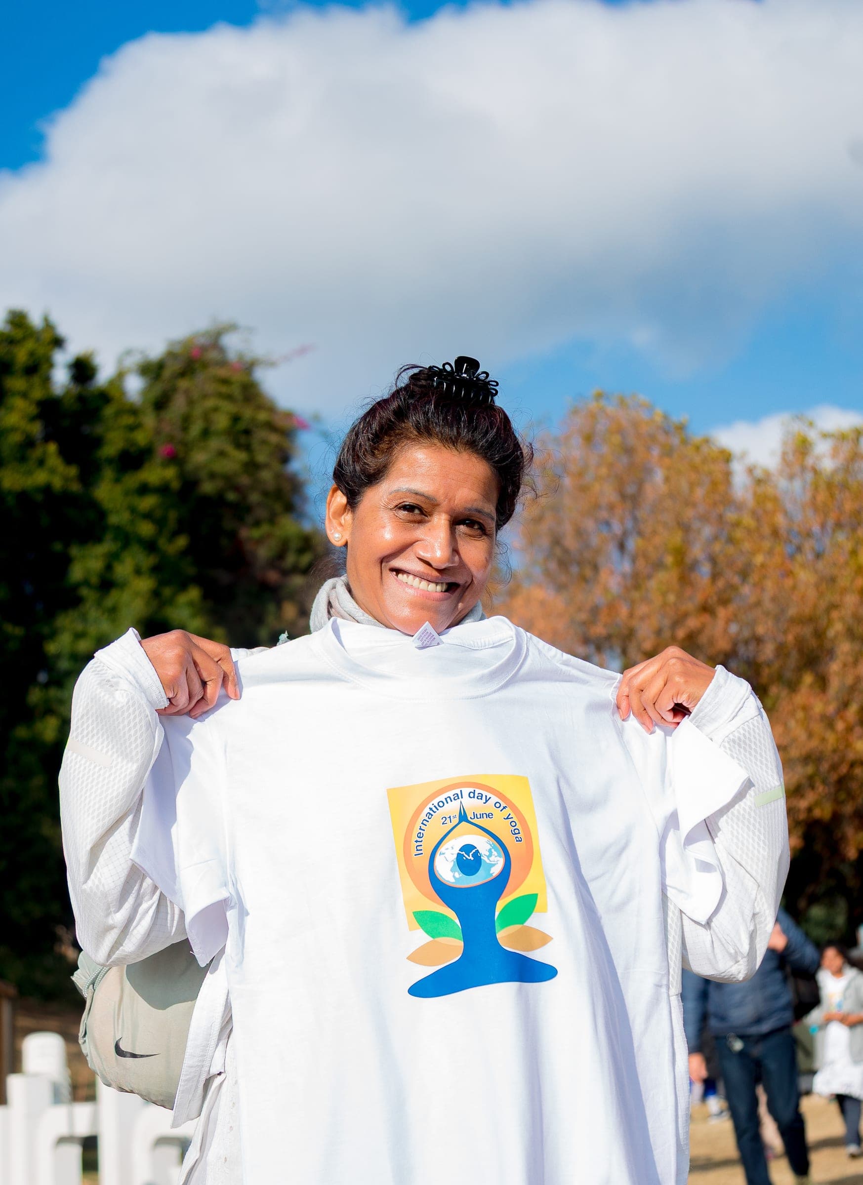 Woman smiling while holding up an International Yoga Day t-shirt